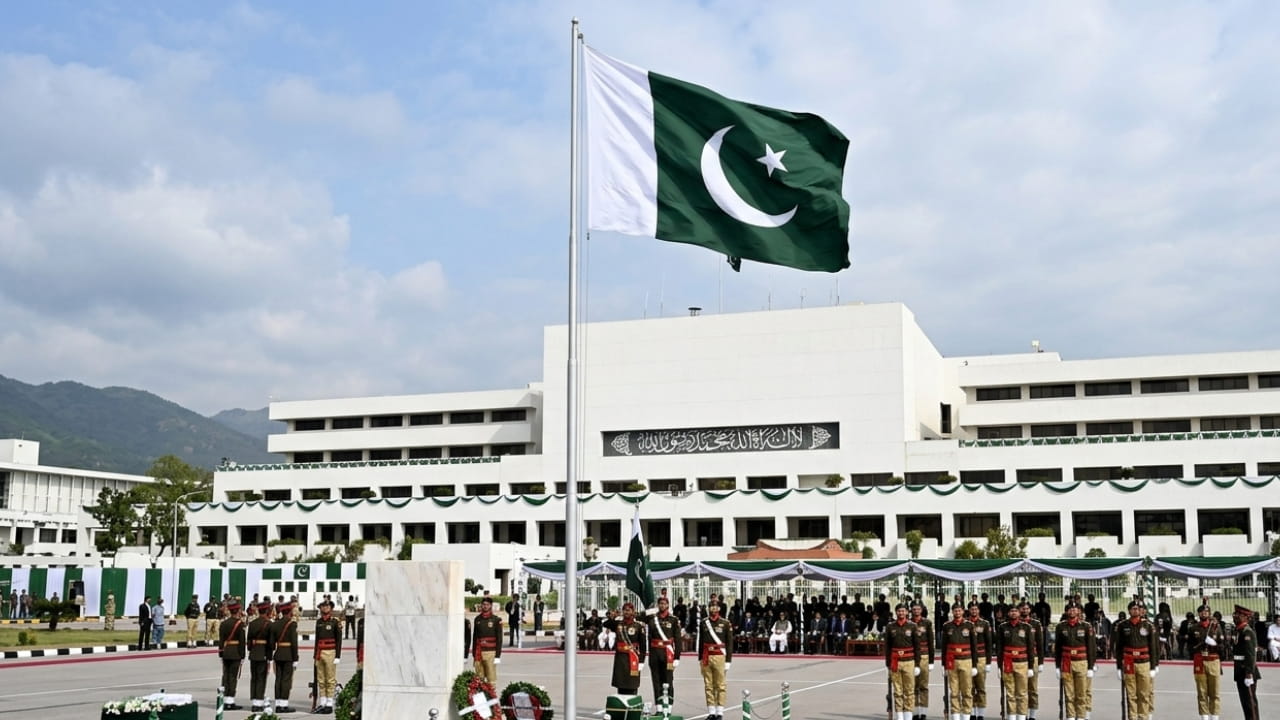 The national flag of Pakistan waving in front of the Parliament house, symbolizing a solemn Pakistan Day observation